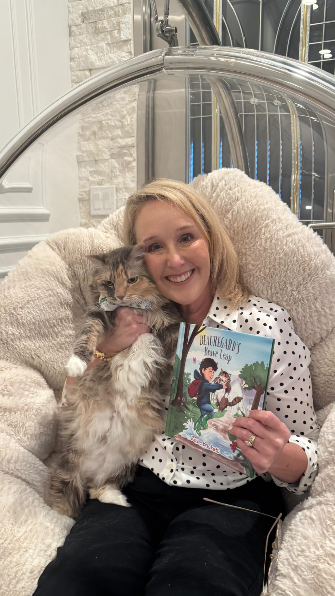 Author Rosie Baskett smiling while holding her cat and a copy of Beauregard's Brave Leap.